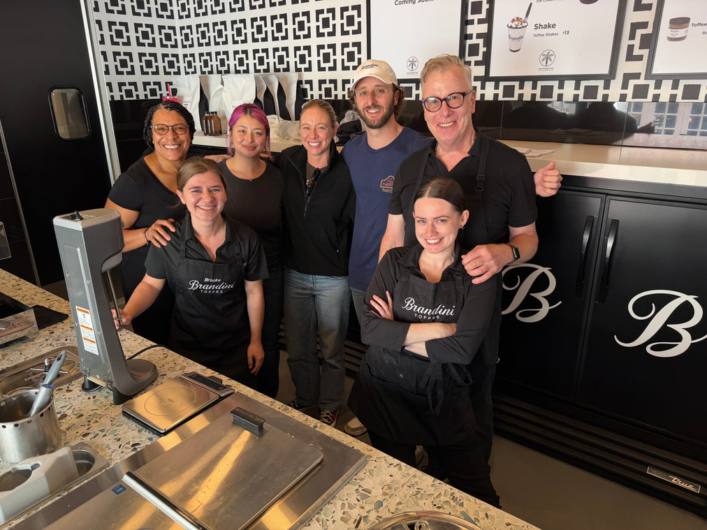 Group of people posing in a kitchen with branded aprons